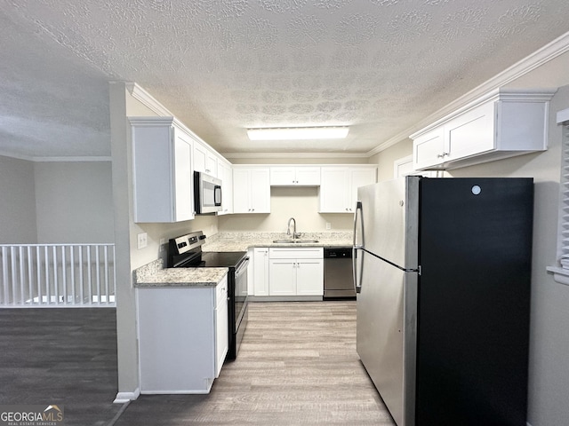 kitchen featuring appliances with stainless steel finishes, light wood-type flooring, a textured ceiling, sink, and white cabinets