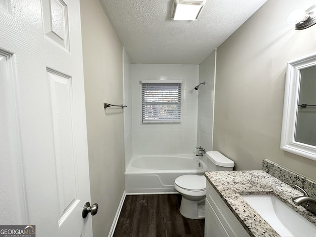 full bathroom with tiled shower / bath combo, a textured ceiling, toilet, vanity, and hardwood / wood-style flooring