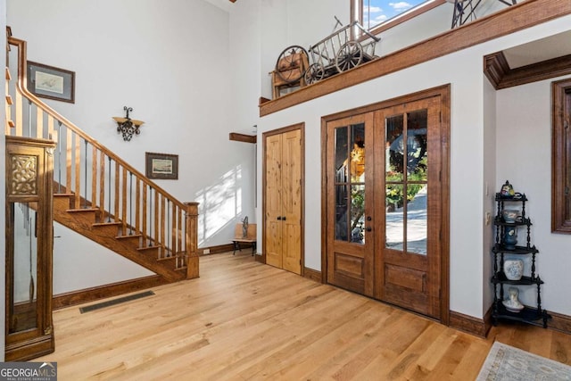 entryway featuring light hardwood / wood-style flooring, a high ceiling, and french doors