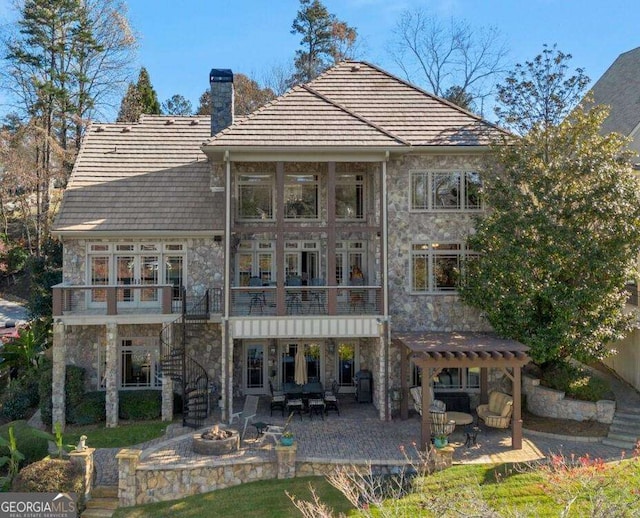 rear view of property featuring a patio area, a balcony, and a fire pit