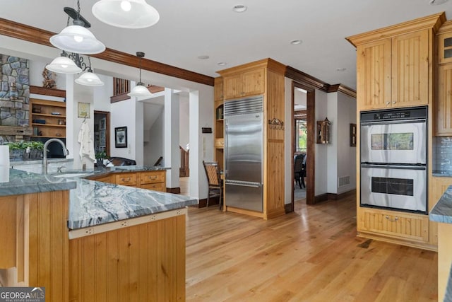 kitchen with kitchen peninsula, ornamental molding, stainless steel appliances, sink, and decorative light fixtures