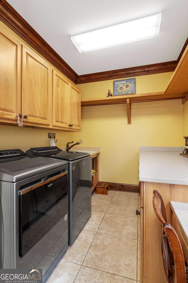 washroom with cabinets, washer and dryer, crown molding, and light tile patterned flooring