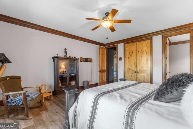 bedroom featuring ceiling fan, light wood-type flooring, crown molding, and a closet