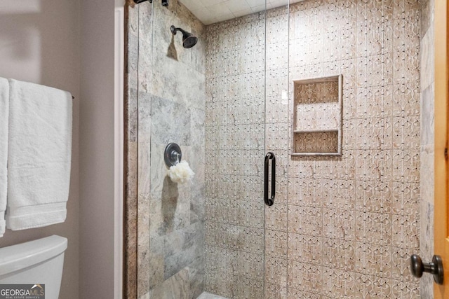 bathroom with toilet and a shower with shower door