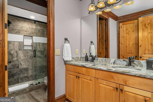 bathroom featuring vanity, toilet, a shower with shower door, and crown molding