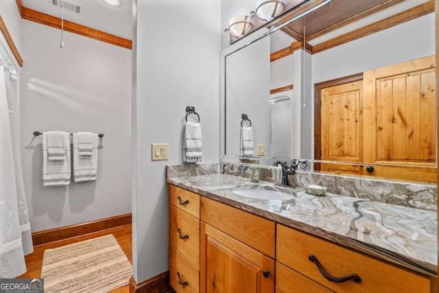 bathroom featuring wood-type flooring, vanity, and crown molding