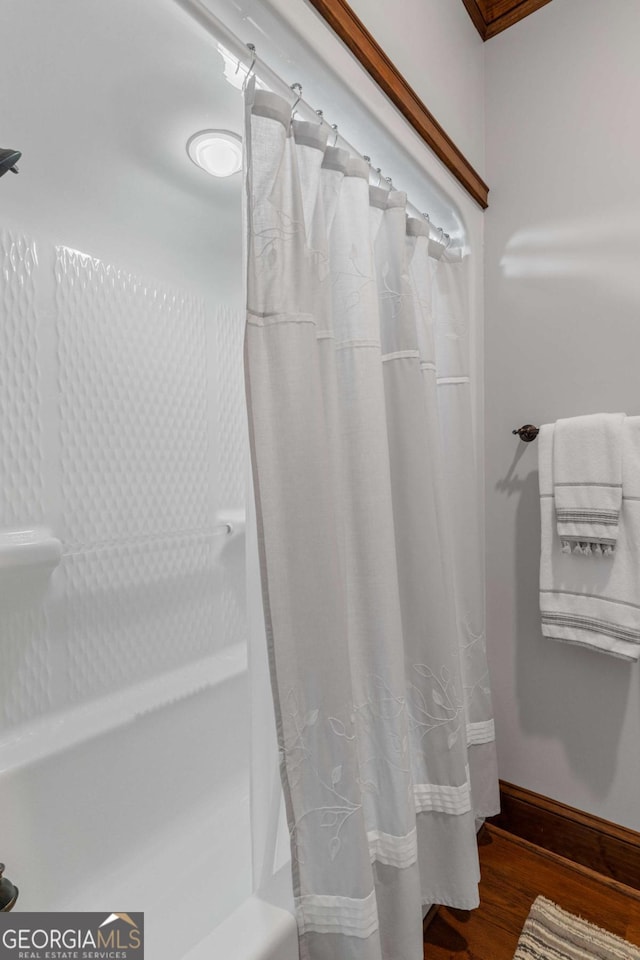 bathroom featuring wood-type flooring and shower / tub combo