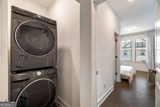 clothes washing area with dark wood-type flooring and stacked washing maching and dryer