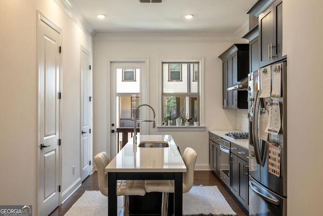 kitchen with sink, dark wood-type flooring, stainless steel appliances, and ornamental molding