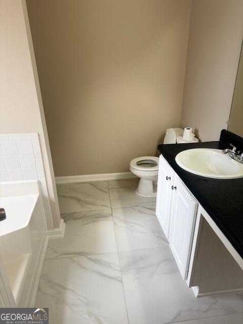 bathroom featuring vanity, toilet, and a tub to relax in