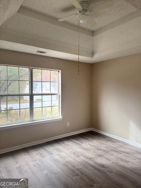 unfurnished room with ceiling fan, a raised ceiling, and wood-type flooring