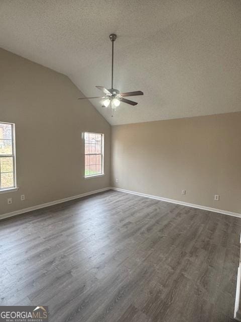 empty room featuring a textured ceiling, dark hardwood / wood-style flooring, vaulted ceiling, and ceiling fan