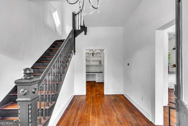 stairs with plenty of natural light, wood-type flooring, and an inviting chandelier