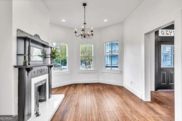 unfurnished living room with wood-type flooring and an inviting chandelier