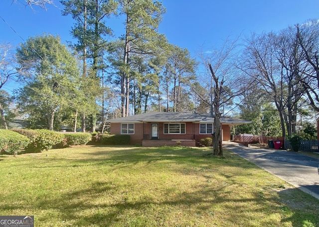 ranch-style house featuring a front yard, fence, brick siding, and driveway