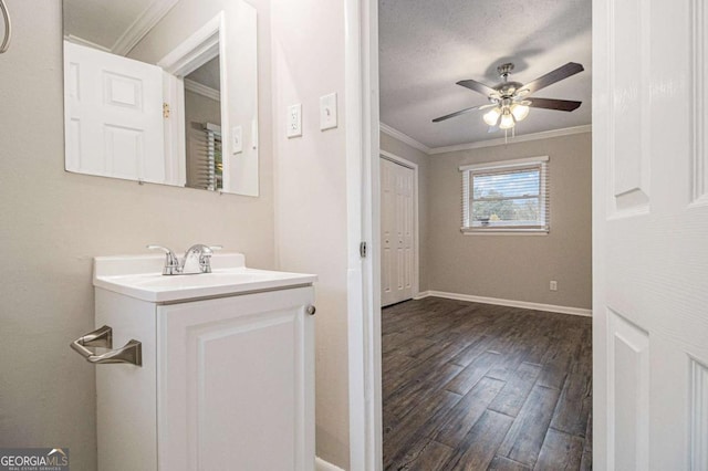 bathroom with ceiling fan, crown molding, a textured ceiling, vanity, and hardwood / wood-style flooring