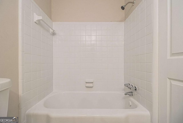 bathroom with tiled shower / bath combo and toilet