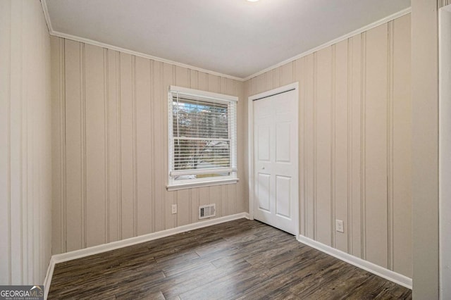 unfurnished bedroom with a closet, dark hardwood / wood-style floors, and ornamental molding