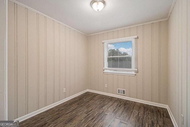 empty room with dark hardwood / wood-style flooring and crown molding