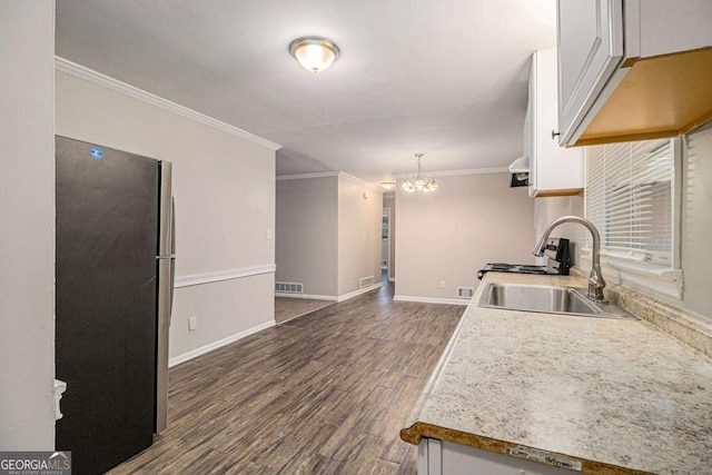 kitchen featuring stainless steel fridge, dark wood-type flooring, sink, an inviting chandelier, and white cabinets