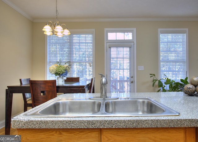 kitchen with pendant lighting, sink, ornamental molding, and an inviting chandelier