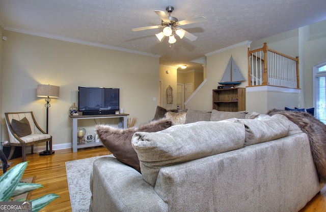 living room featuring hardwood / wood-style flooring, ceiling fan, crown molding, and a textured ceiling