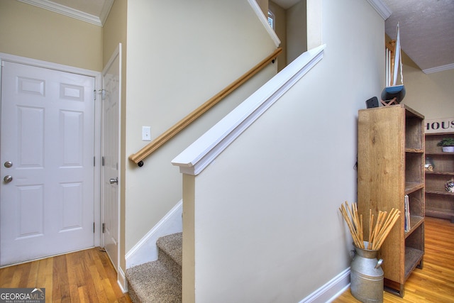 stairs featuring hardwood / wood-style floors and ornamental molding