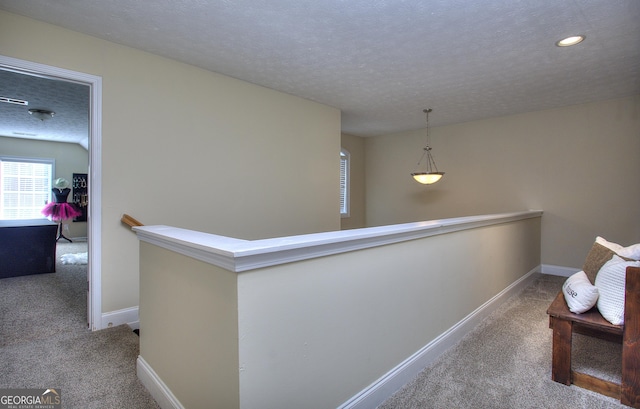 hallway featuring carpet and a textured ceiling