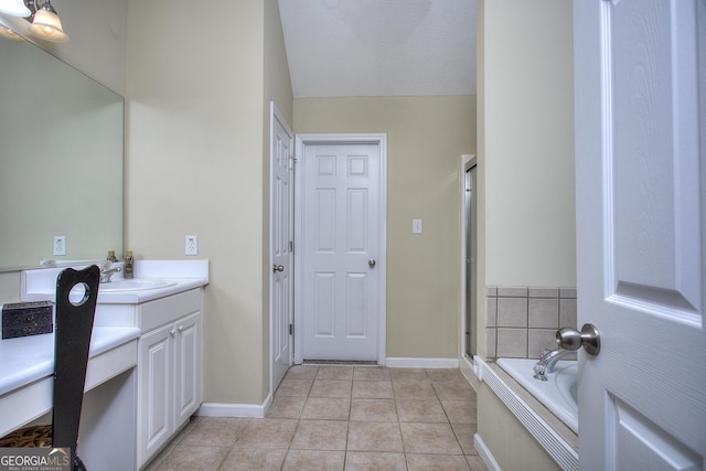 bathroom with tile patterned floors, a washtub, vanity, and a textured ceiling