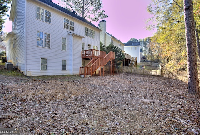 back house at dusk with a wooden deck and central AC