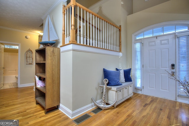 foyer with crown molding, light hardwood / wood-style flooring, and a textured ceiling