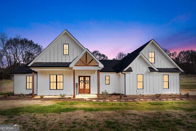 modern farmhouse style home with covered porch and a yard