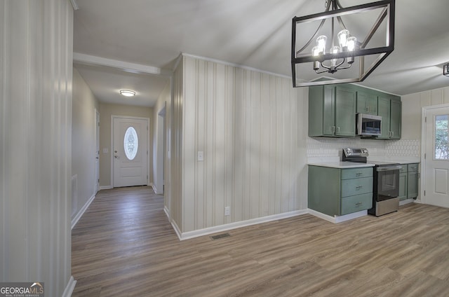 kitchen featuring backsplash, light wood-type flooring, green cabinetry, and appliances with stainless steel finishes