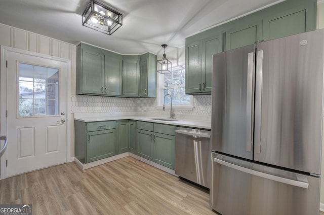 kitchen with appliances with stainless steel finishes, hanging light fixtures, green cabinets, and sink