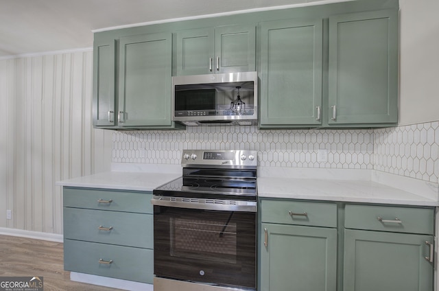 kitchen with backsplash, light hardwood / wood-style flooring, appliances with stainless steel finishes, and green cabinetry