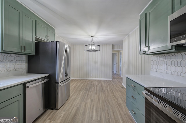 kitchen with decorative light fixtures, light wood-type flooring, stainless steel appliances, and green cabinets