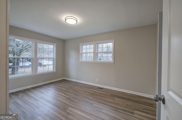 empty room with dark hardwood / wood-style floors and a wealth of natural light