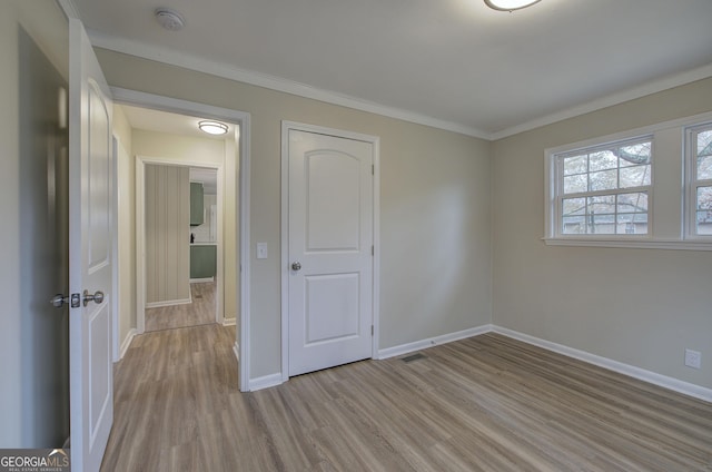 unfurnished bedroom with a closet, light hardwood / wood-style flooring, and ornamental molding