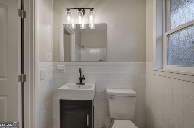 bathroom featuring vanity, toilet, and tile walls