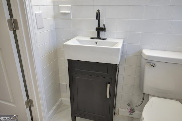 bathroom with vanity, toilet, and tile walls