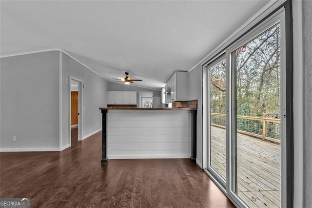 unfurnished living room featuring ceiling fan, dark wood-type flooring, and vaulted ceiling