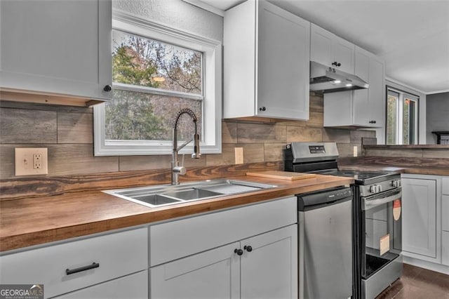 kitchen with butcher block counters, white cabinetry, sink, and stainless steel appliances