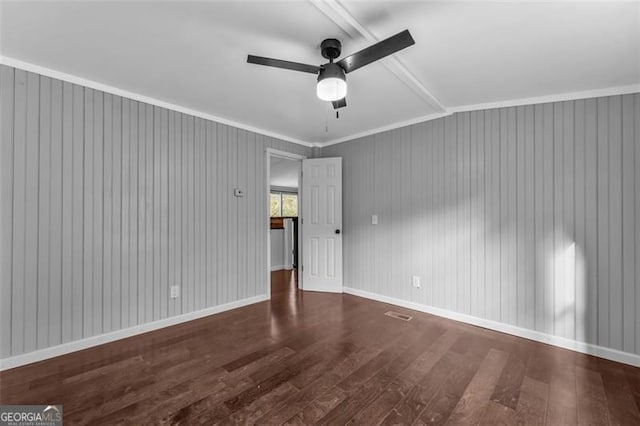 unfurnished room featuring wood walls, lofted ceiling, crown molding, dark hardwood / wood-style floors, and ceiling fan