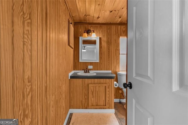 bathroom with vanity, wooden ceiling, and wooden walls