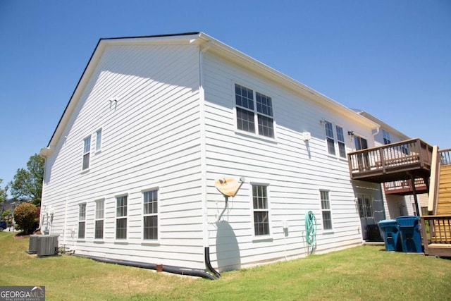 rear view of property featuring central air condition unit, a deck, and a lawn