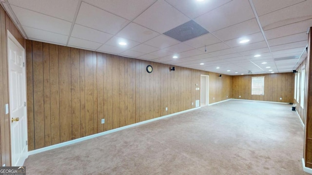 basement with a paneled ceiling, carpet floors, and wooden walls