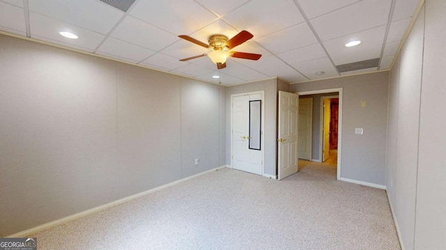 empty room with a paneled ceiling, ceiling fan, and light carpet