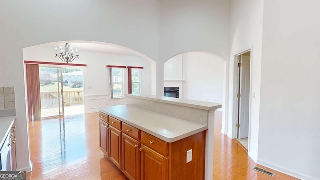 kitchen with a center island, a high ceiling, light hardwood / wood-style flooring, a chandelier, and decorative light fixtures