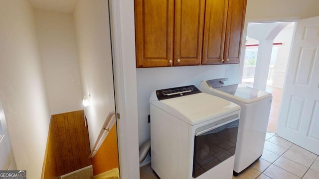 washroom with cabinets, washer and dryer, and light tile patterned flooring