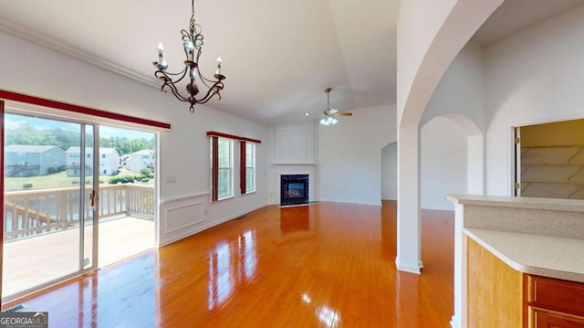 unfurnished living room featuring plenty of natural light, light hardwood / wood-style floors, lofted ceiling, and ceiling fan with notable chandelier